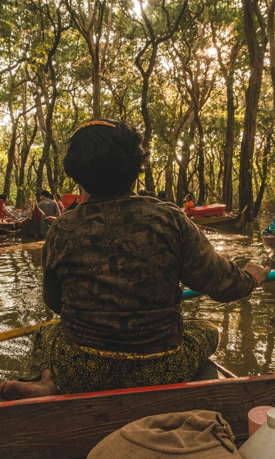 A guest in a canoe under the flooded forest at Kompong Phluk