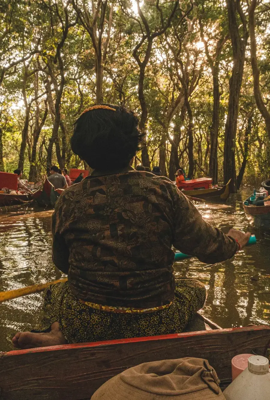 A guest in a canoe under the flooded forest at Kompong Phluk