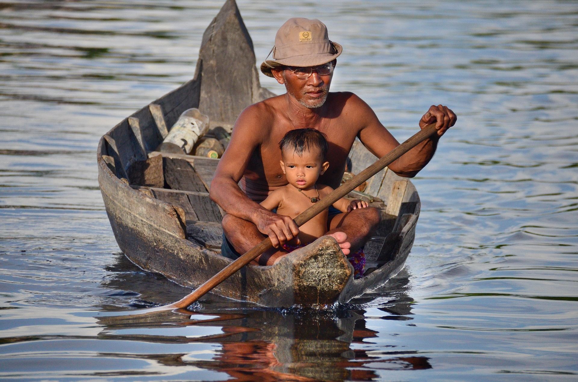 Man Canoes with Son in Floating Village